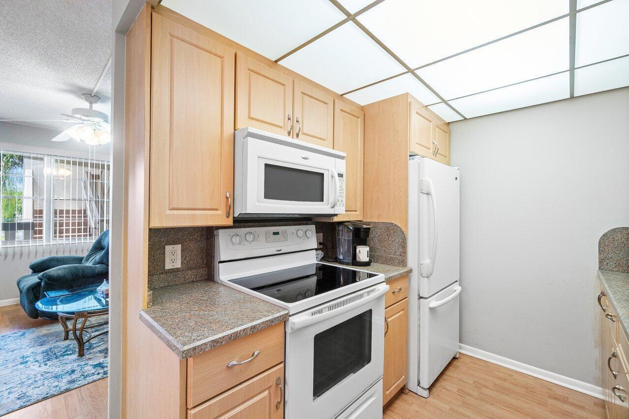 A kitchen with light wood cabinets, white appliances, and a speckled laminate countertop — 2046 Rexford C, Boca Raton FL 33434, BOCA RATON, FL