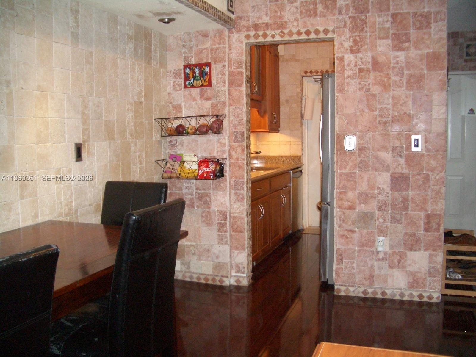 A dining area with stone-tiled walls leads into a kitchen with wooden cabinets — 10900 SW 104th St # 324, Miami FL 33176, MIAMI, FL