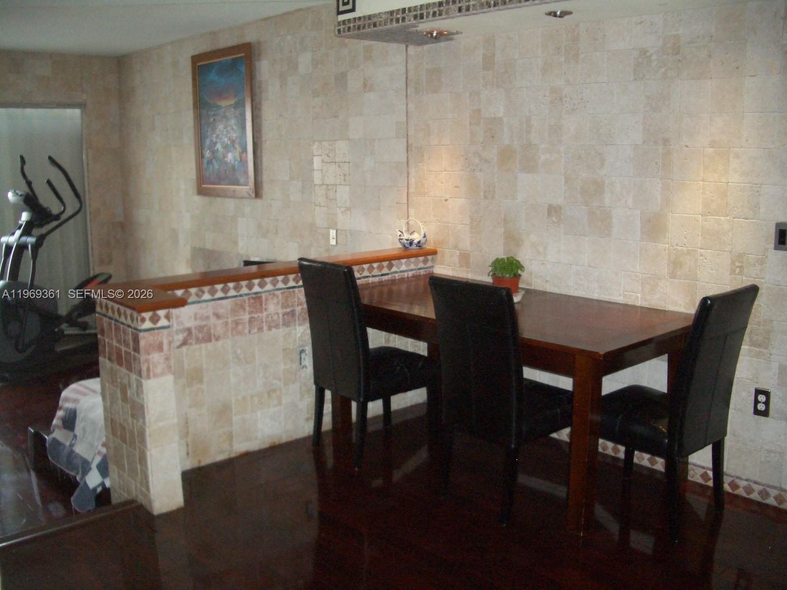 A dining area features a wooden table, black chairs, and a tiled half-wall partition — 10900 SW 104th St # 324, Miami FL 33176, MIAMI, FL