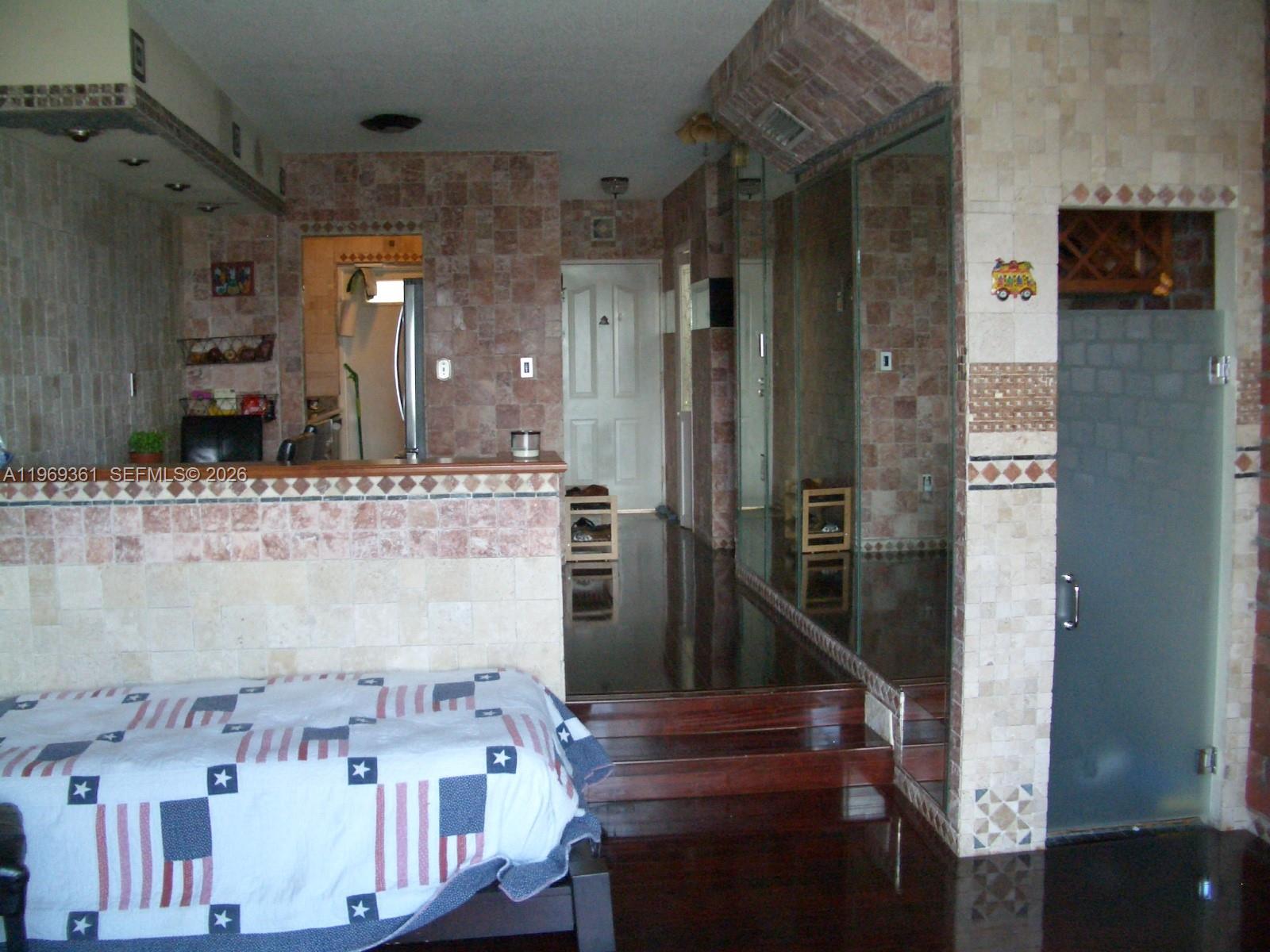 A room features tiled walls, a raised wooden floor, and a bed with a flag quilt — 10900 SW 104th St # 324, Miami FL 33176, MIAMI, FL