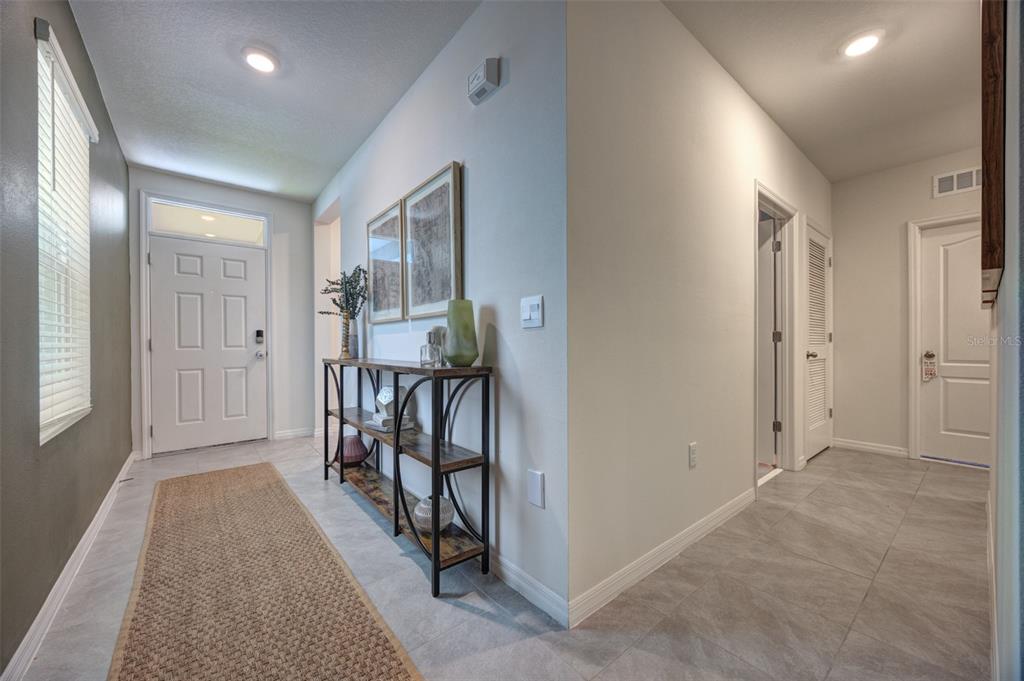 A bright entryway features tile flooring, a console table, and a white front door — 372 PELHAM PARK DRIVE, DELAND, FL