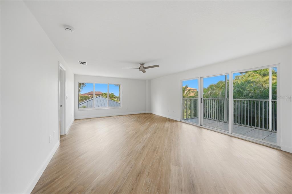 An aerial view shows three multi-story apartment buildings situated along a waterfront with green lawns — 1477 PARK BEACH CIRCLE UNIT 13, PUNTA GORDA, FL