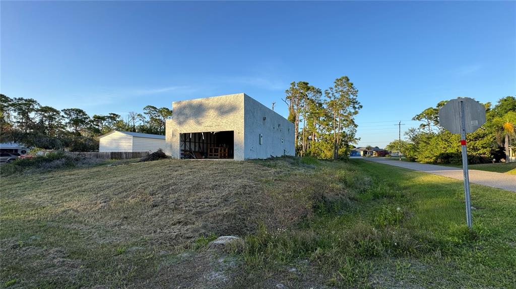 A concrete block structure stands on a grassy lot next to a paved road — 5182 HOPKINS AVENUE, PORT CHARLOTTE, FL