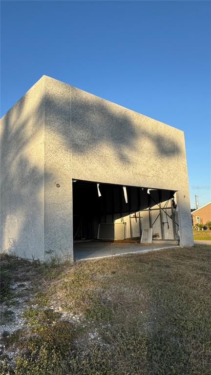 An exterior view of a detached garage with a large open bay and stucco finish — 5182 HOPKINS AVENUE, PORT CHARLOTTE, FL