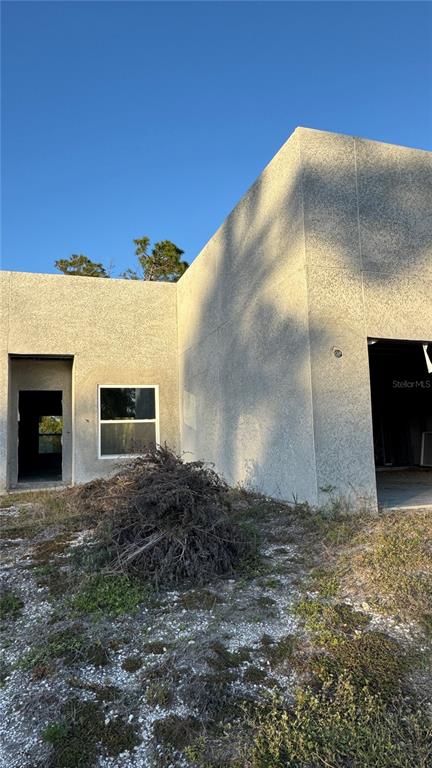 The exterior of a modern, unfinished concrete house features a large garage opening and window — 5182 HOPKINS AVENUE, PORT CHARLOTTE, FL