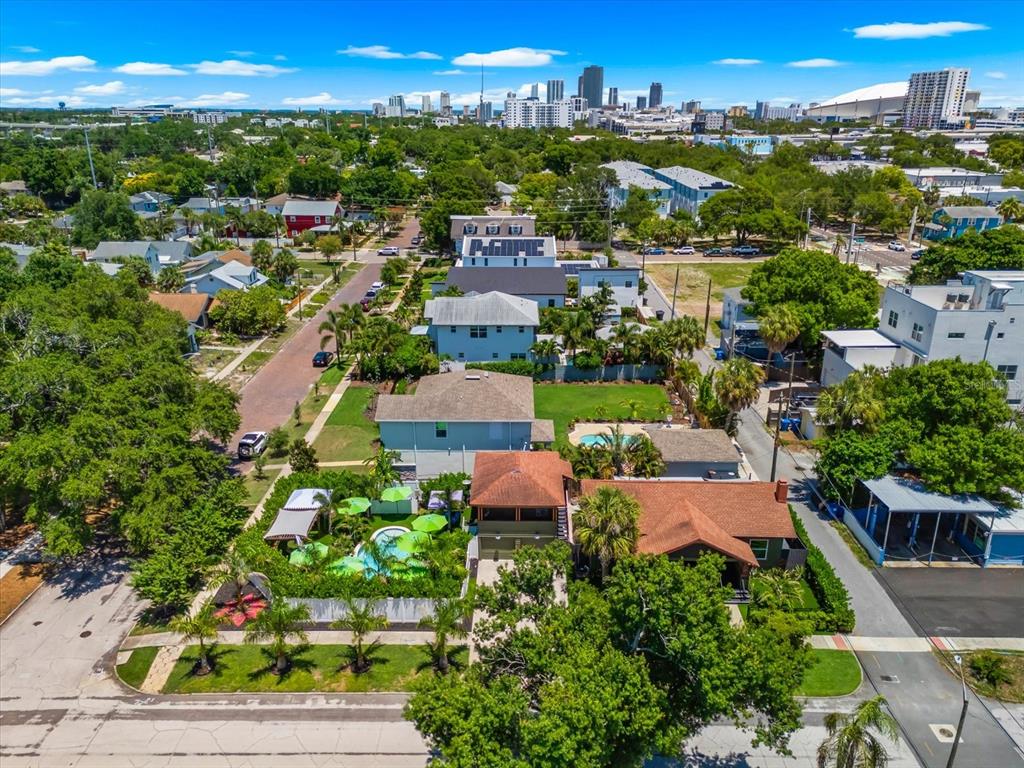 An aerial view shows a residential neighborhood with houses, swimming pools, and a city skyline — 127 23RD STREET N, ST PETERSBURG, FL