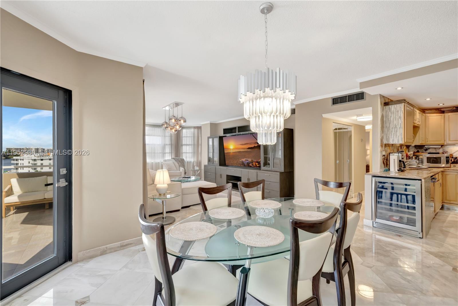 A dining area with a glass table and chandelier opens to a living room and kitchen — 1965 S Ocean Dr # 4S, Hallandale Beach FL 33009, HALLANDALE BEACH, FL