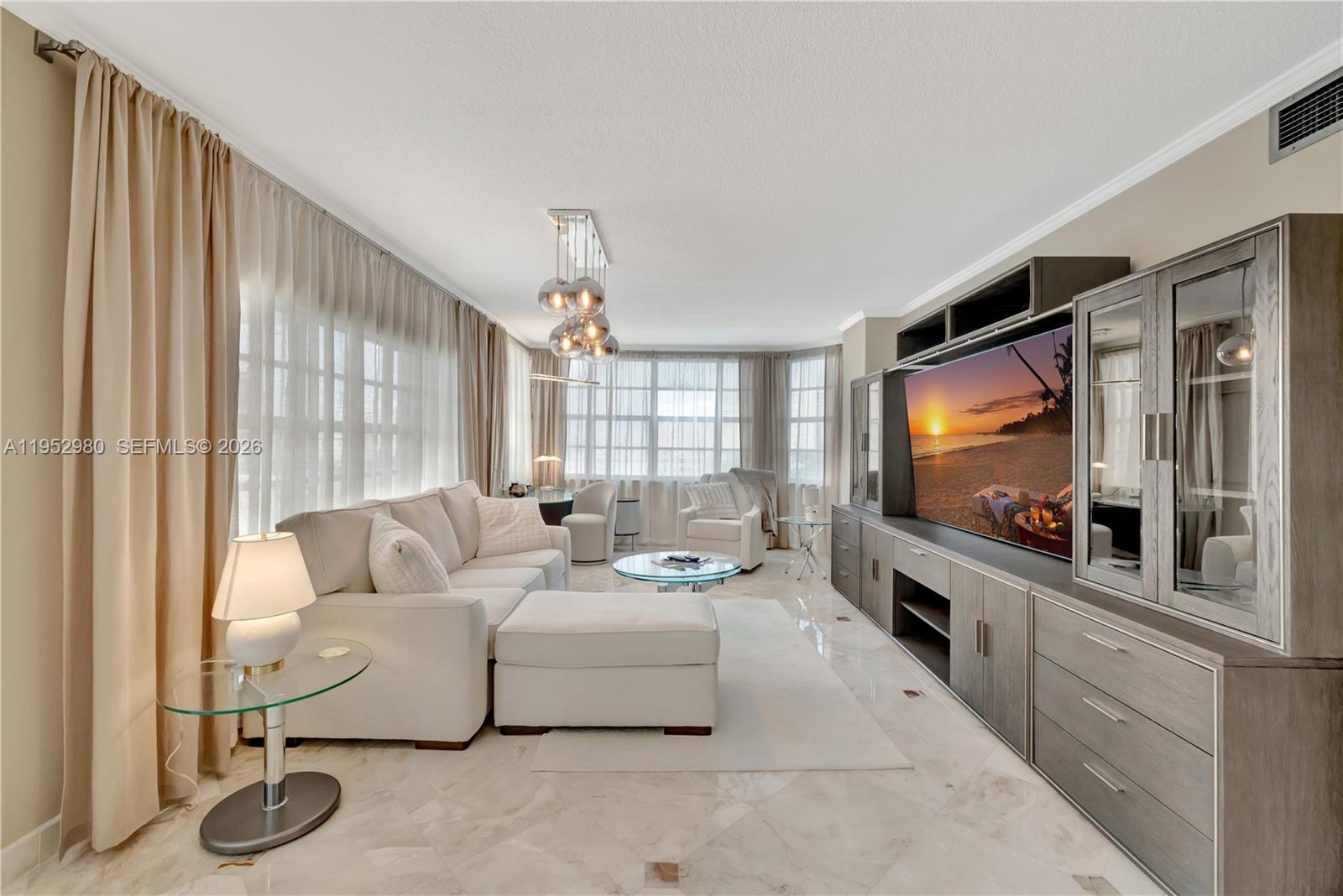 A living room features a white sectional sofa, a large media console, and floor-to-ceiling curtains — 1965 S Ocean Dr # 4S, Hallandale Beach FL 33009, HALLANDALE BEACH, FL