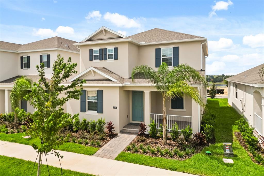 A two-story suburban house with a tan exterior, blue shutters, and a front porch — 17055 HAGGERTY HOLLOW, WINTER GARDEN, FL