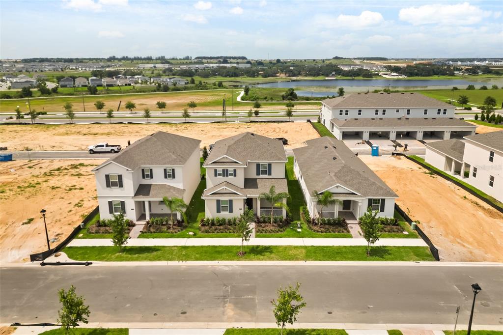 An aerial view shows three newly constructed suburban houses with landscaped front yards and driveways — 17055 HAGGERTY HOLLOW, WINTER GARDEN, FL