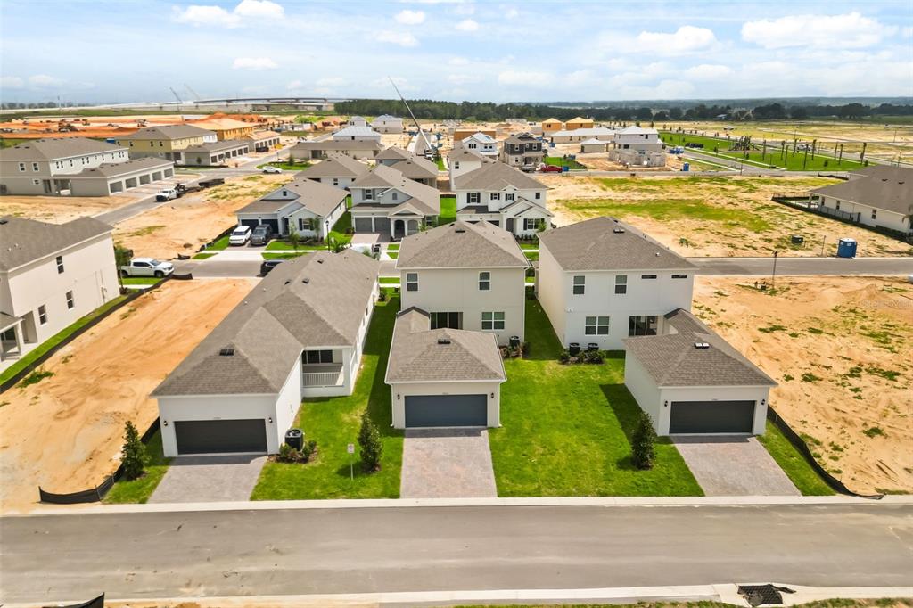 An aerial view shows three new suburban houses with driveways and lawns under construction — 17055 HAGGERTY HOLLOW, WINTER GARDEN, FL