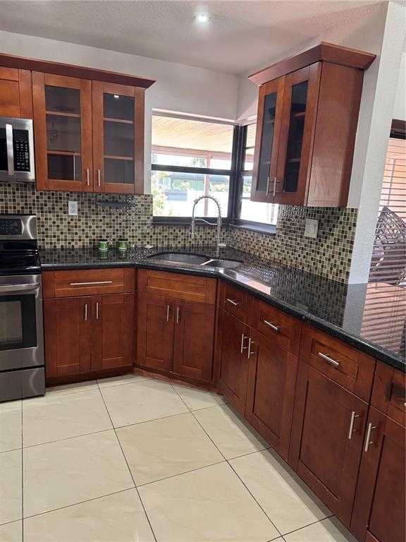 A kitchen features cherry wood cabinets, dark granite countertops, and a mosaic tile backsplash — 8240 NW 181ST STREET, HIALEAH, FL