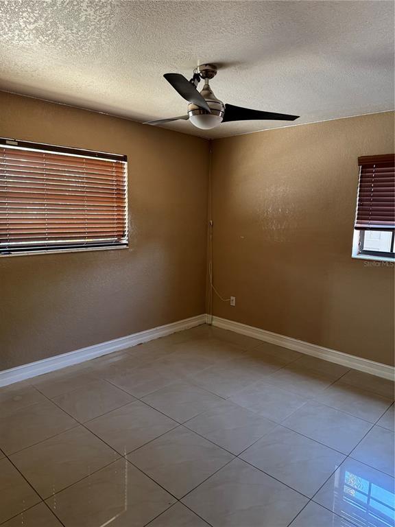 An empty room features tan walls, large light-colored floor tiles, and a ceiling fan — 8240 NW 181ST STREET, HIALEAH, FL