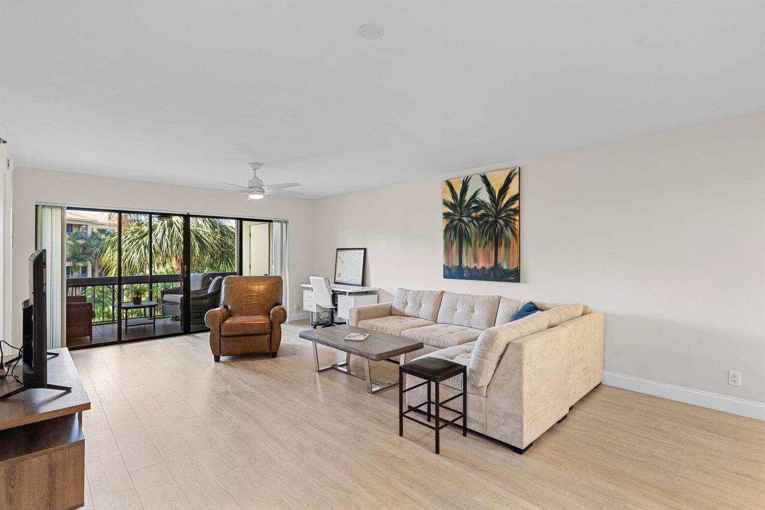A living room features light wood flooring, a beige sectional sofa, and a sliding glass door — 700 Uno Lago Drive # 303, Juno Beach FL 33408, JUNO BEACH, FL