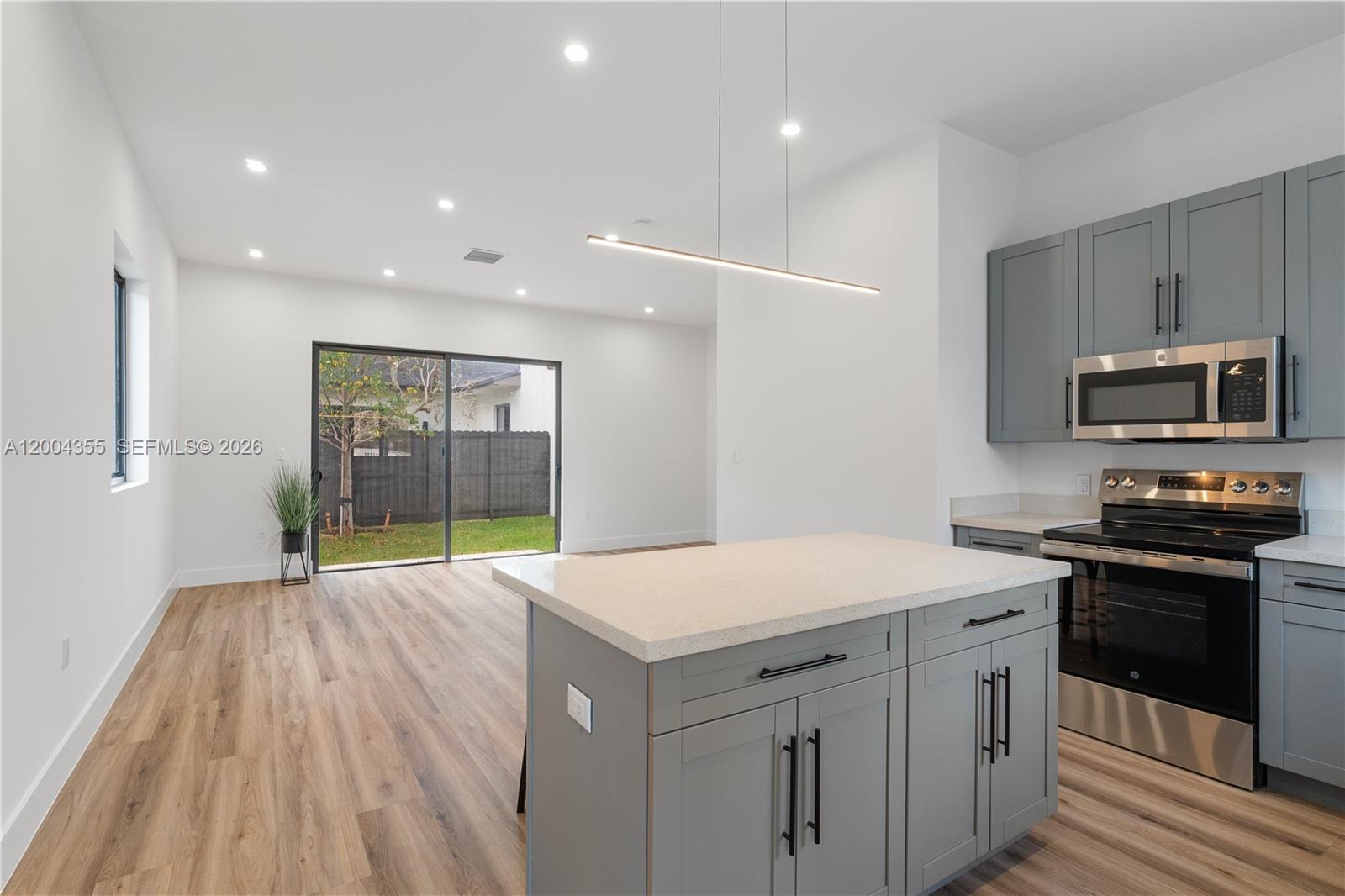 A modern kitchen features gray cabinets, stainless steel appliances, and an island with quartz countertops — 4518 NW 4 ST, Miami FL 33126, MIAMI, FL