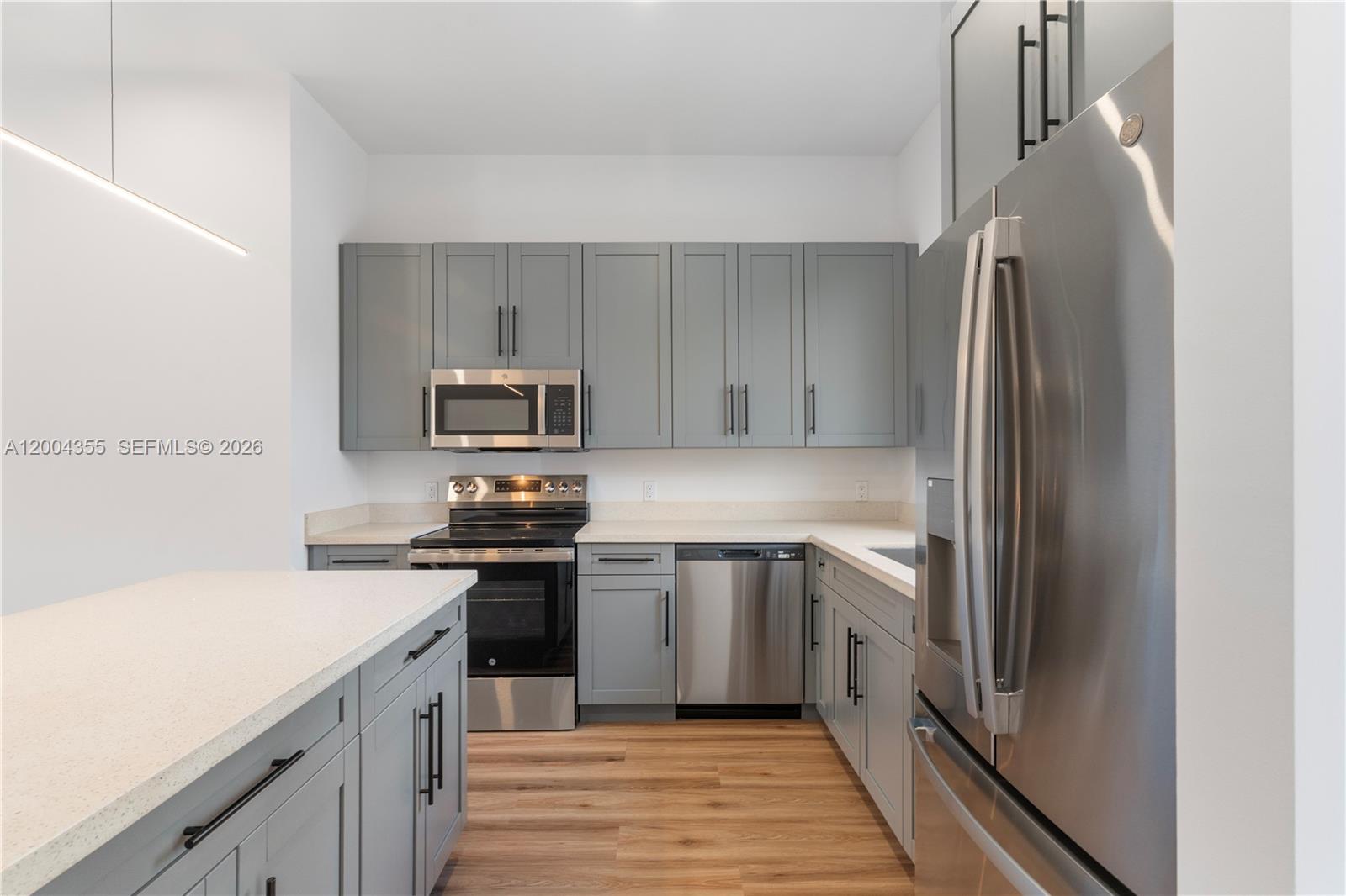 A modern kitchen features gray cabinets, stainless steel appliances, and light-colored countertops — 4518 NW 4 ST, Miami FL 33126, MIAMI, FL