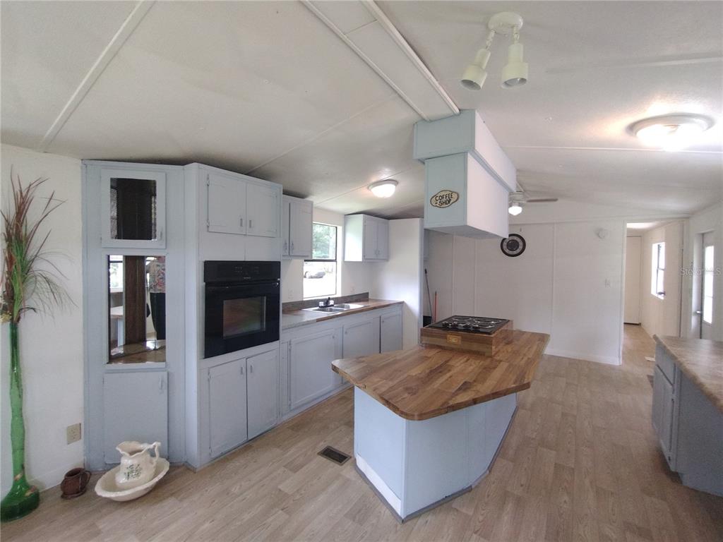 A kitchen features light blue cabinets, a wooden island countertop, and a built-in wall oven — 172 ESTATES AVENUE, BROOKSVILLE, FL