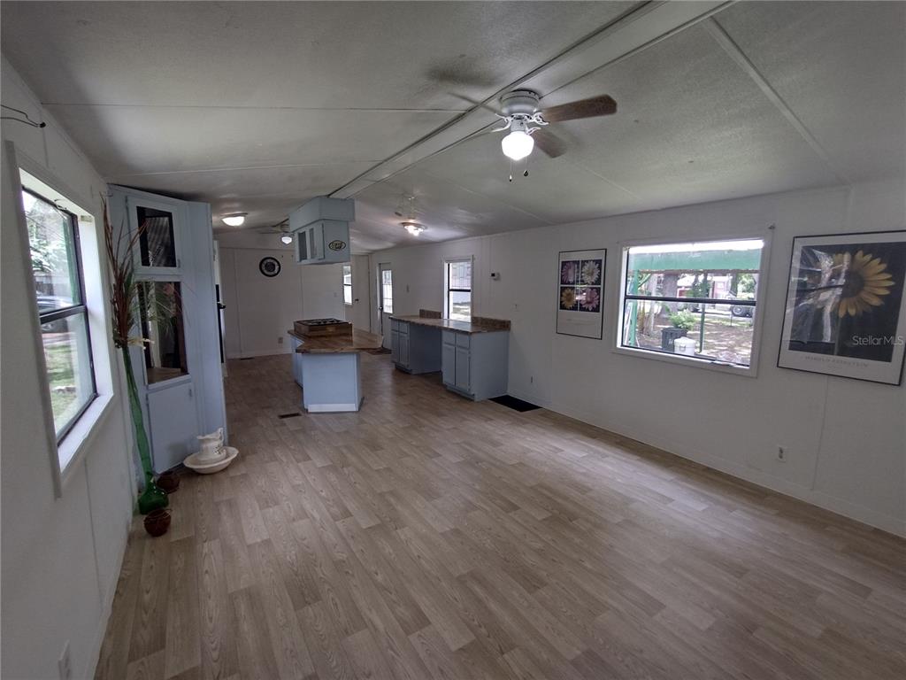 A kitchen and living area with light wood flooring, blue cabinets, and a ceiling fan — 172 ESTATES AVENUE, BROOKSVILLE, FL