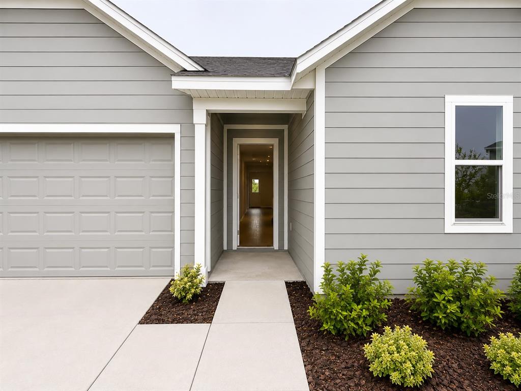 A gray-sided house exterior features a garage, a recessed entryway, and a single window — 431 ARTEMIS STREET, LAKE WALES, FL