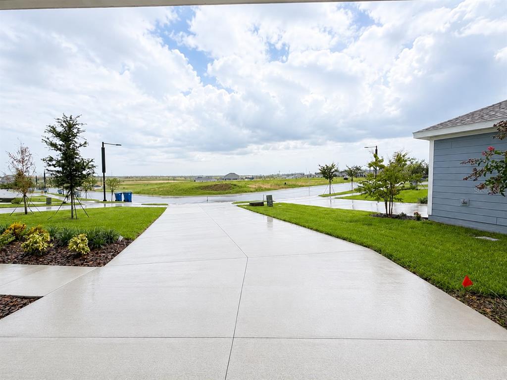 A concrete driveway leads toward a residential street under a cloudy sky — 431 ARTEMIS STREET, LAKE WALES, FL