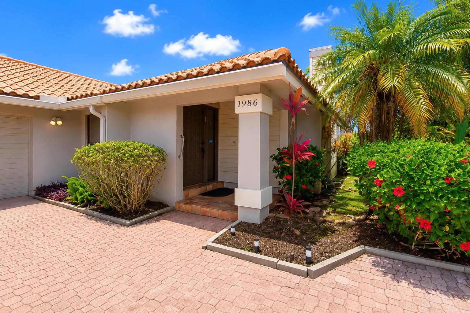 A single-story house exterior with a tiled roof, paved driveway, and tropical landscaping — 7986 Palacio Del Mar Drive, Boca Raton FL 33433, BOCA RATON, FL