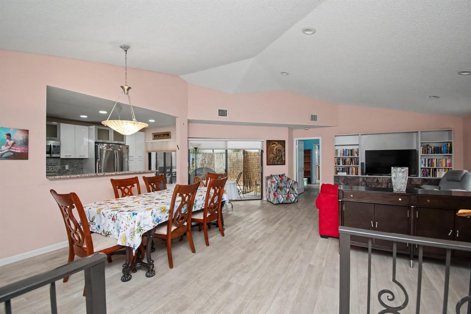 A dining area and living room feature light wood-look flooring, pink walls, and vaulted ceilings — 7986 Palacio Del Mar Drive, Boca Raton FL 33433, BOCA RATON, FL