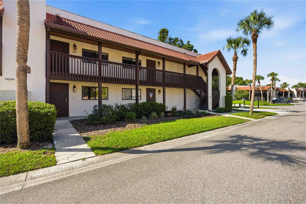 A two-story apartment building with a brown balcony, tile roof, and palm trees — 6204 COUNTRY CLUB DRIVE UNIT F24, LAKE WALES, FL