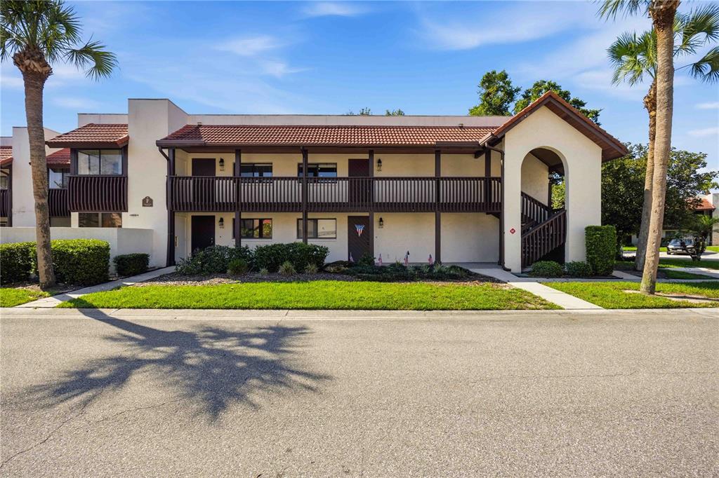A two-story apartment building with a brown balcony, tile roof, and palm trees — 6204 COUNTRY CLUB DRIVE UNIT F24, LAKE WALES, FL