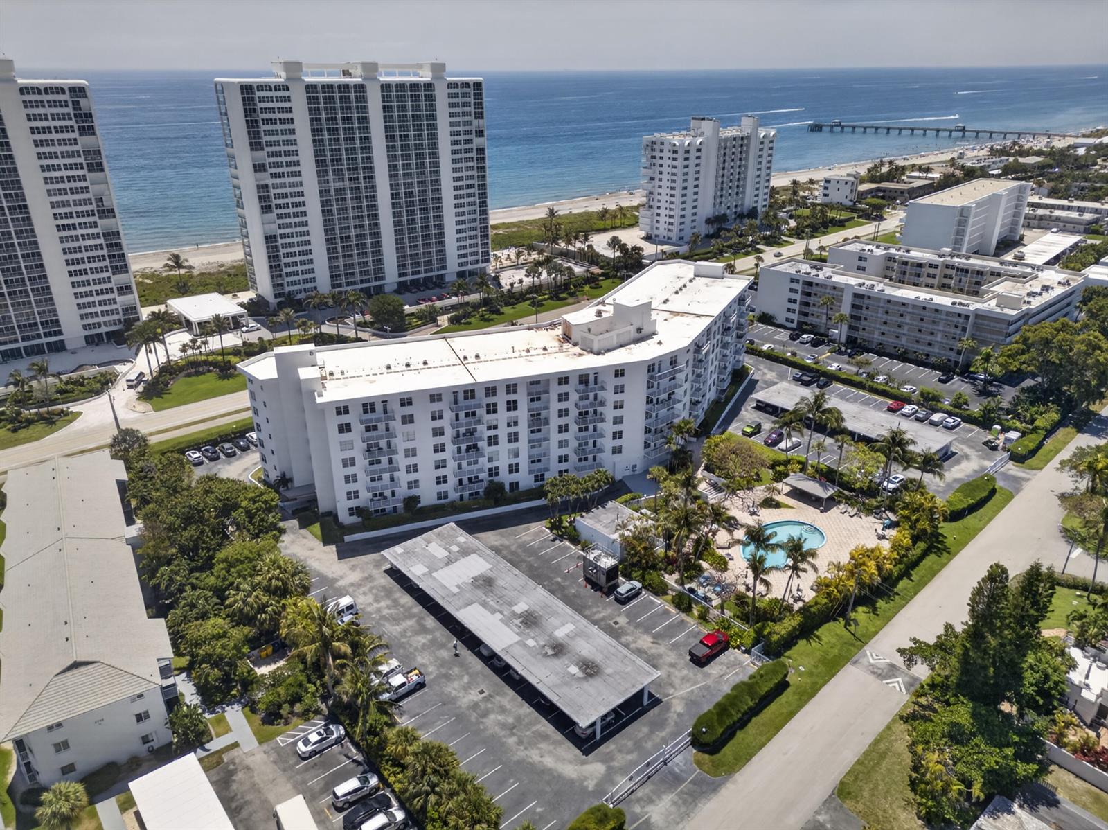 An aerial view shows multiple white apartment buildings, a swimming pool, and parking lots near the ocean — 2851 S Ocean Boulevard # 1n, Boca Raton FL 33432, BOCA RATON, FL
