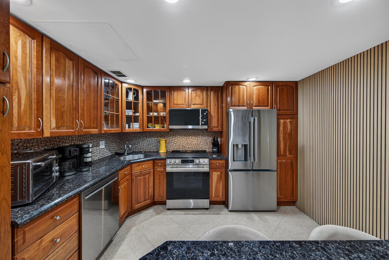 A kitchen features cherry wood cabinets, dark granite countertops, stainless steel appliances, and tiled flooring — 2851 S Ocean Boulevard # 1n, Boca Raton FL 33432, BOCA RATON, FL
