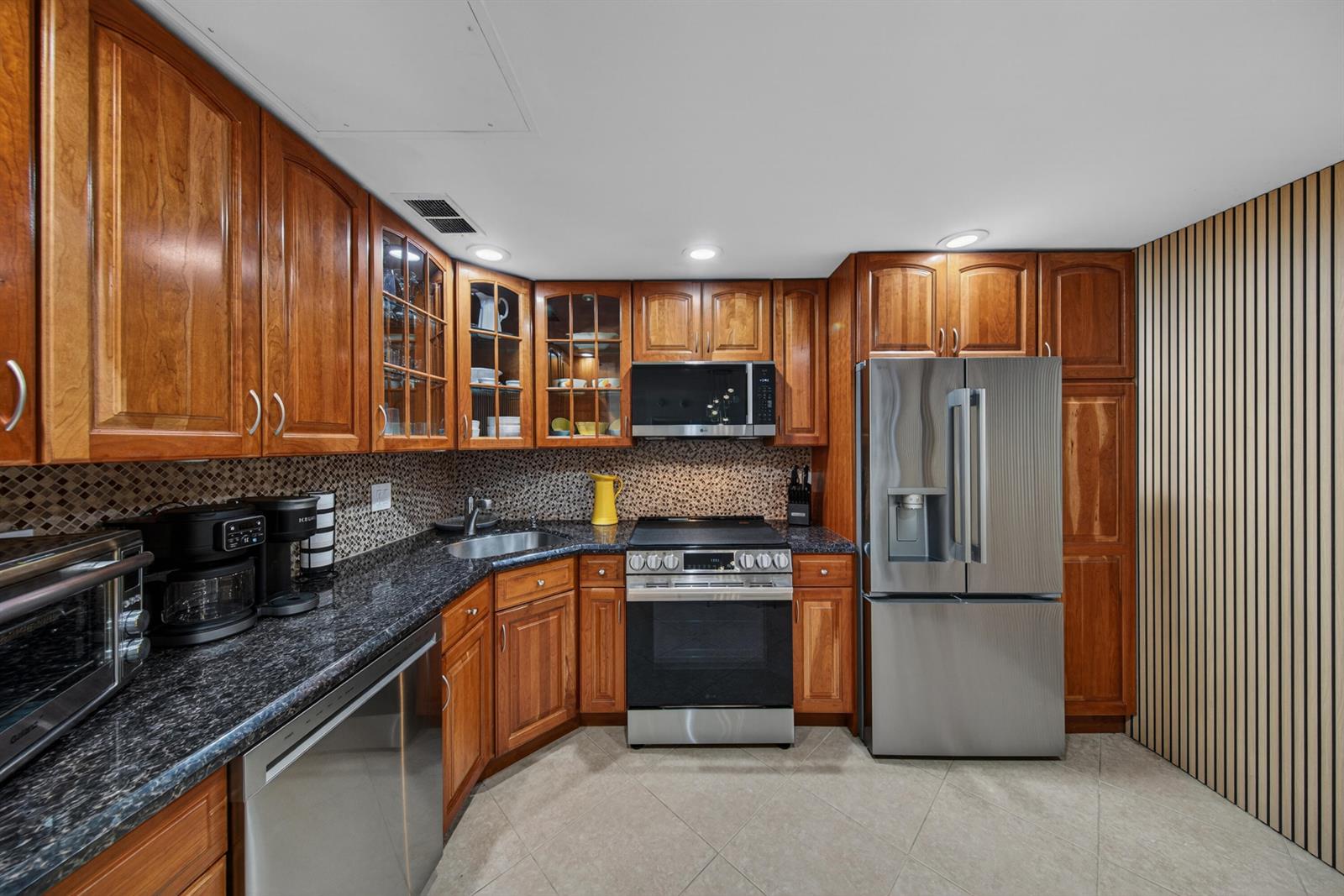 A kitchen features cherry wood cabinets, granite countertops, stainless steel appliances, and a tiled backsplash — 2851 S Ocean Boulevard # 1n, Boca Raton FL 33432, BOCA RATON, FL