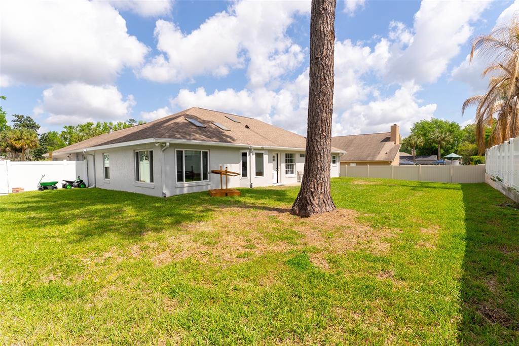The backyard of a single-story house features a large pine tree and a white fence — 1088 SW 32ND LANE, OCALA, FL
