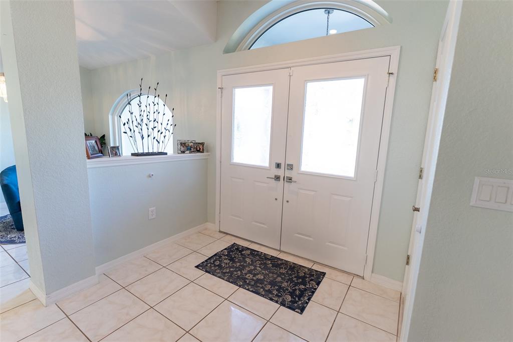 An entryway features white double doors, tiled flooring, and a half-wall with decorative accents — 1088 SW 32ND LANE, OCALA, FL