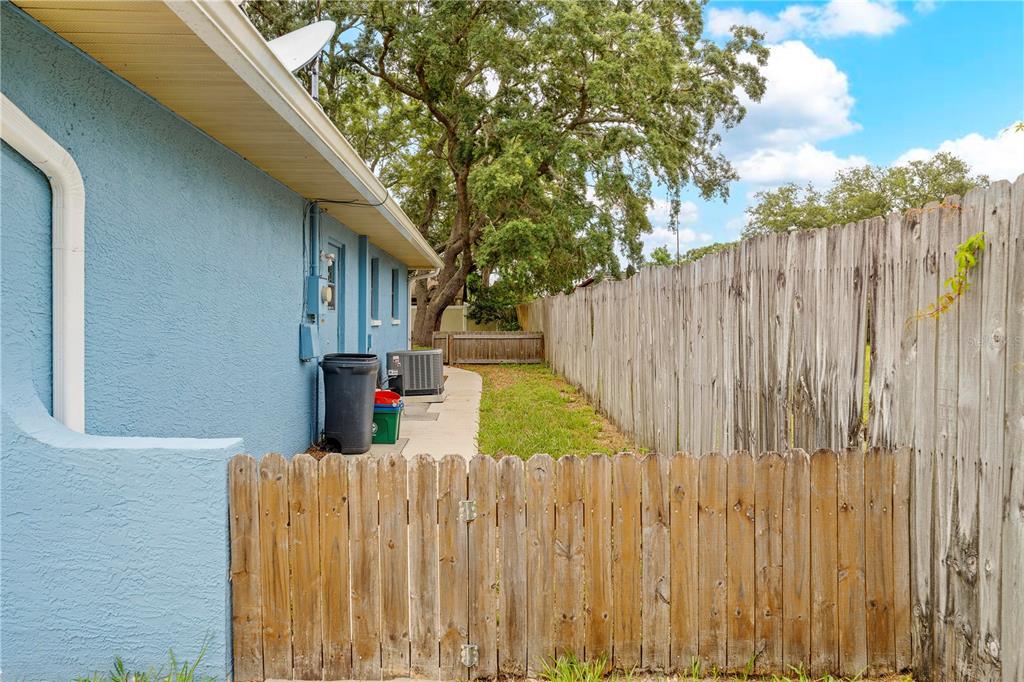 A side view of a blue house exterior with a wooden fence and grassy yard — 9063 PEMBERTON STREET, SPRING HILL, FL