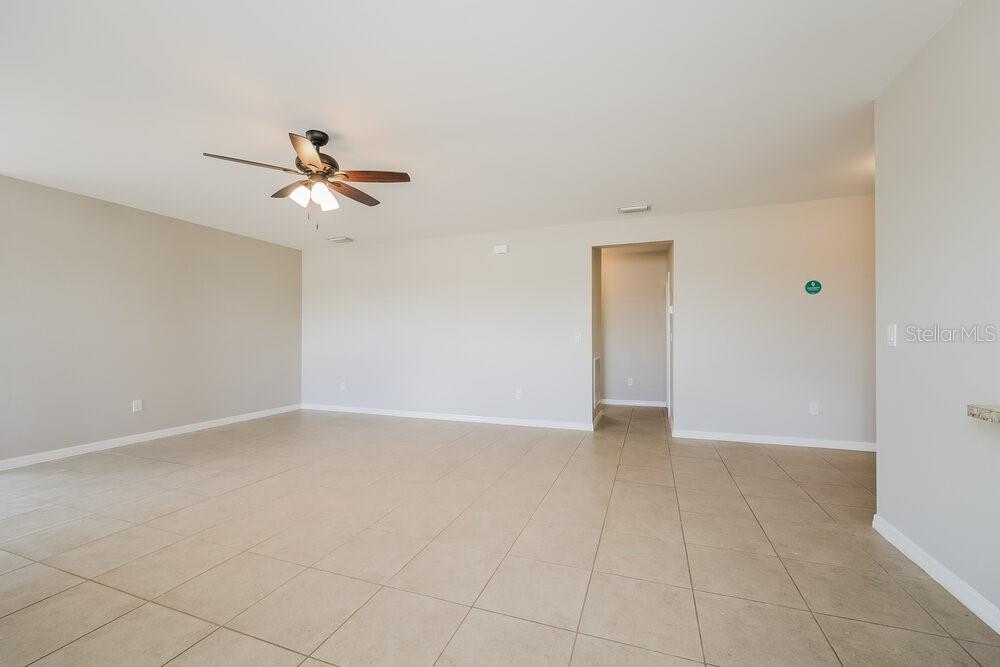 An empty room with beige walls, light tile flooring, and a ceiling fan — 627 SW 27TH TERRACE, CAPE CORAL, FL