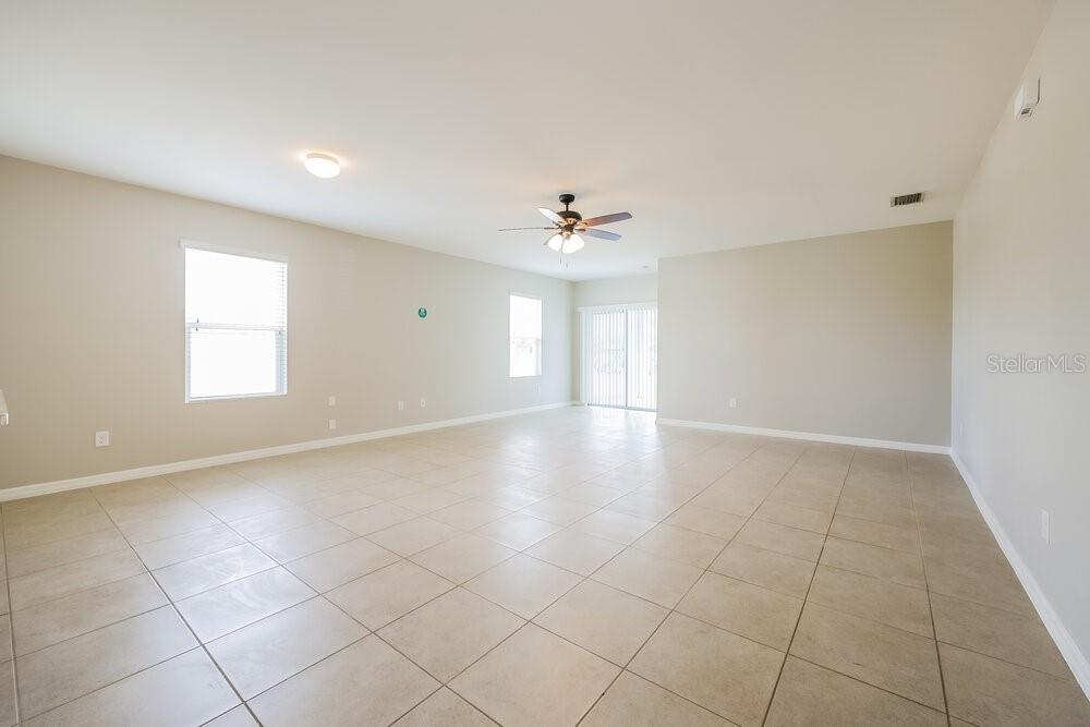 An empty living room features beige walls, large tile flooring, and a ceiling fan — 627 SW 27TH TERRACE, CAPE CORAL, FL