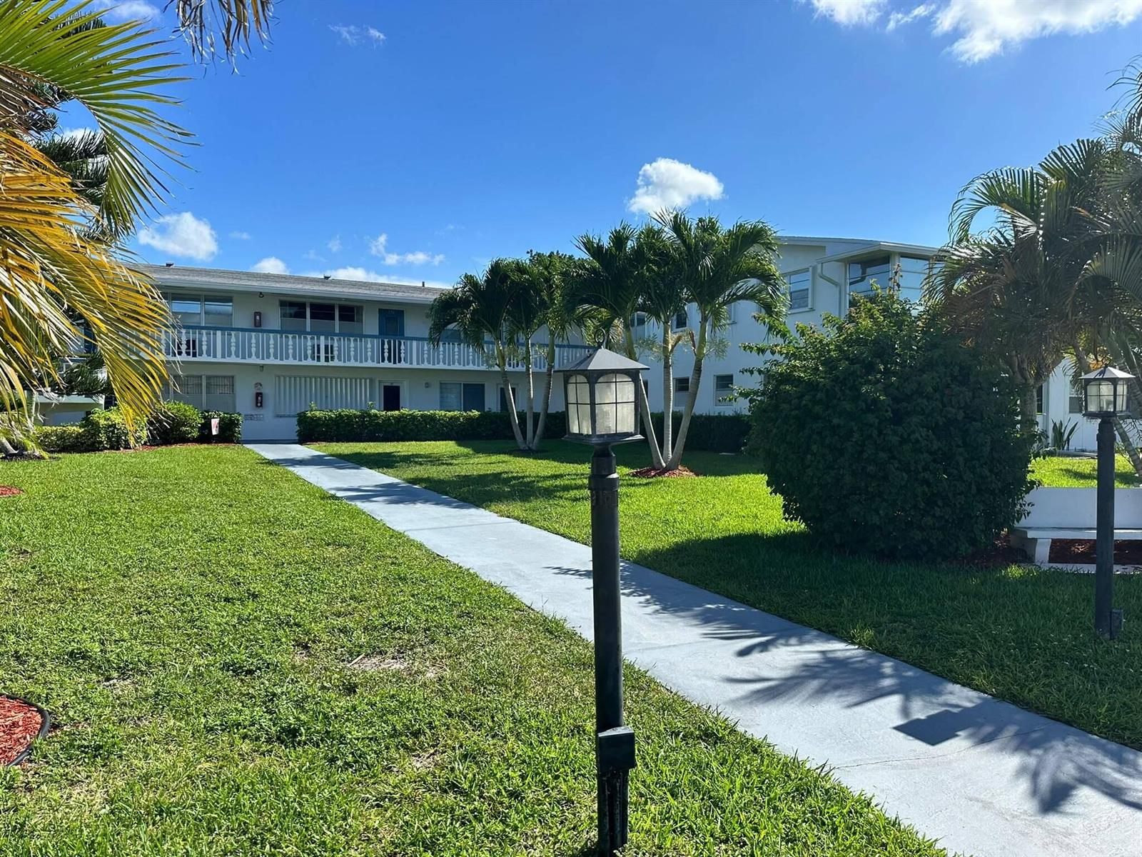 A two-story apartment building with a balcony, palm trees, and a walkway in front — 171 Markham H # 171, Deerfield Beach FL 33442, DEERFIELD BEACH, FL