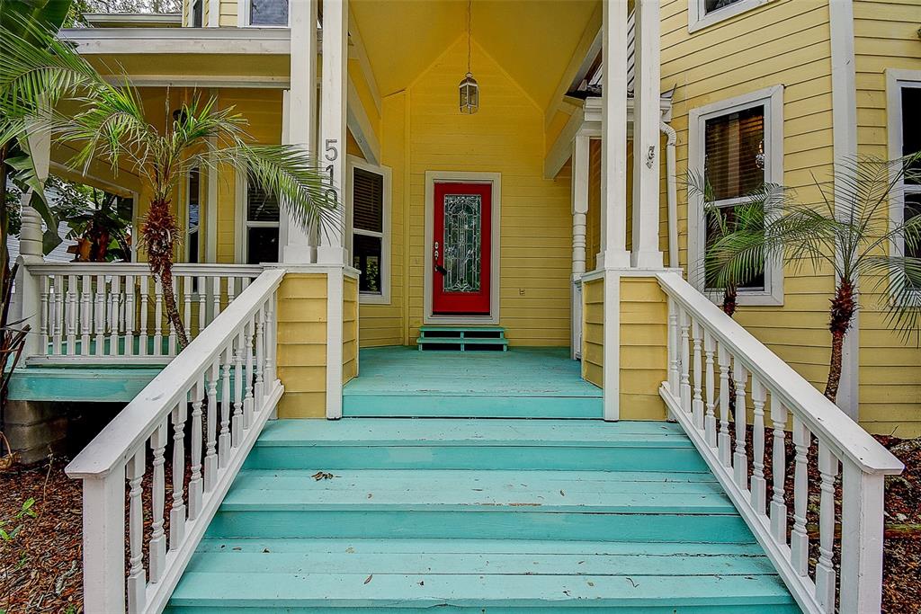 A yellow house features a bright red front door and a wide, turquoise-painted wooden staircase — 510 WIDEVIEW AVENUE, TARPON SPRINGS, FL