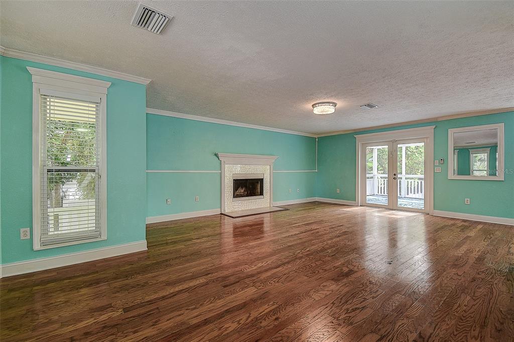 A living room with turquoise walls, hardwood floors, a fireplace, and glass doors to a deck — 510 WIDEVIEW AVENUE, TARPON SPRINGS, FL
