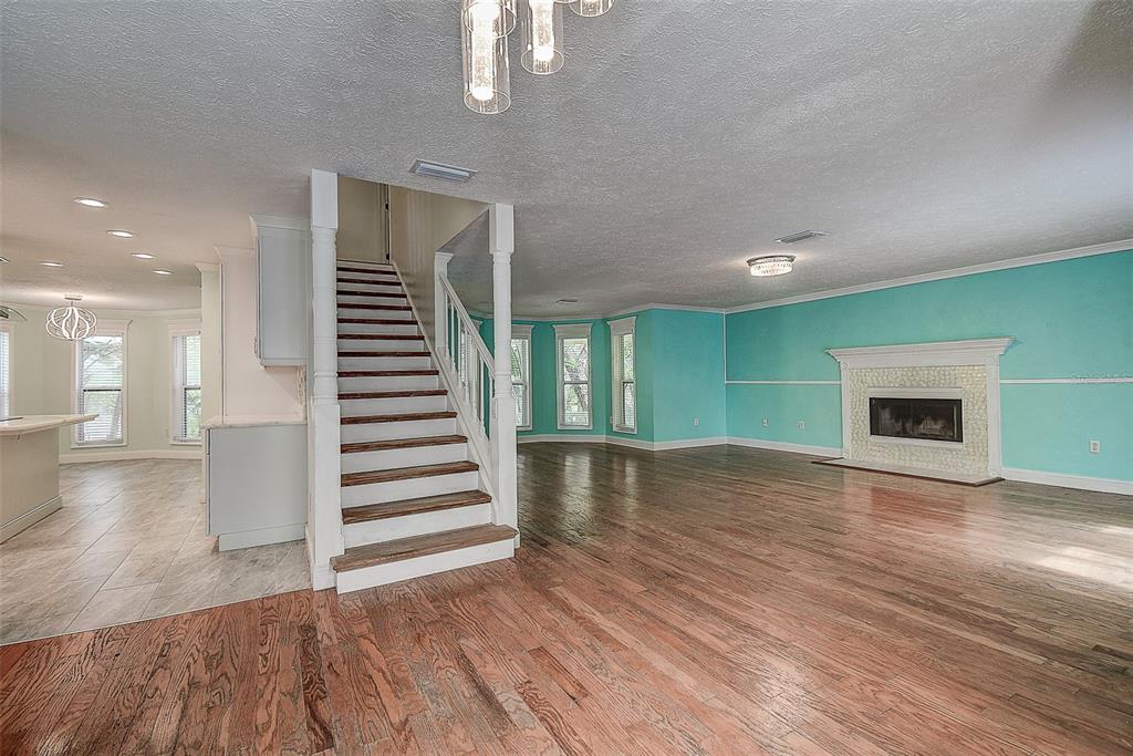A living room with hardwood floors, a fireplace, and a staircase leading to an upper level — 510 WIDEVIEW AVENUE, TARPON SPRINGS, FL