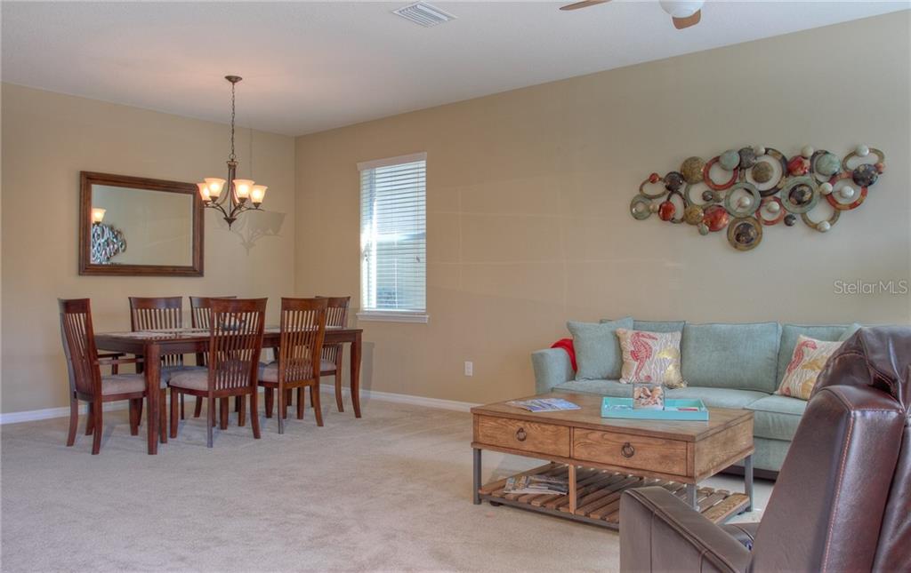 A dining area and living room with a sofa, coffee table, and wall art — 8525 KARPEAL DRIVE, SARASOTA, FL