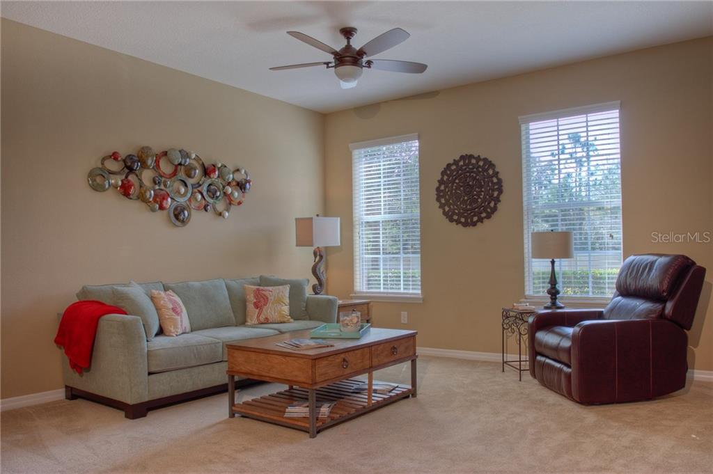 A living room features a light green sofa, a brown leather recliner, and a coffee table — 8525 KARPEAL DRIVE, SARASOTA, FL