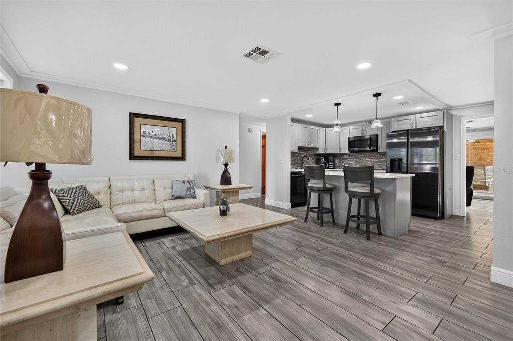 A living room with a white sofa and stone coffee table opens to a kitchen — 11280 FREEDOM COURT, SEMINOLE, FL