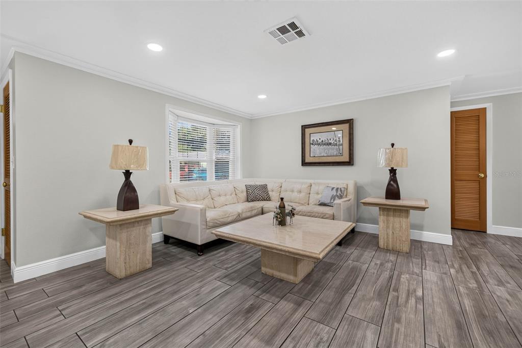 A living room features a beige sectional sofa, a stone coffee table, and wood-look flooring — 11280 FREEDOM COURT, SEMINOLE, FL