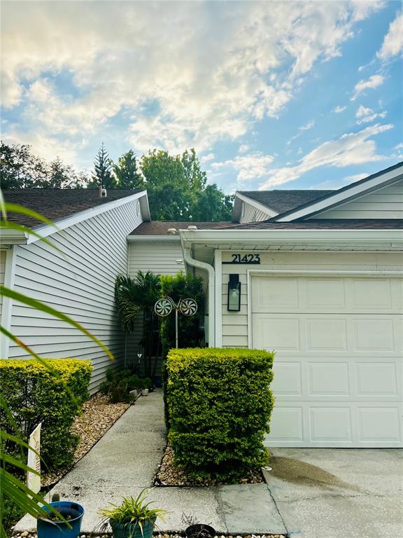 The exterior of a house features a white garage, light siding, and a landscaped walkway — 21423 KEATING WAY, LUTZ, FL
