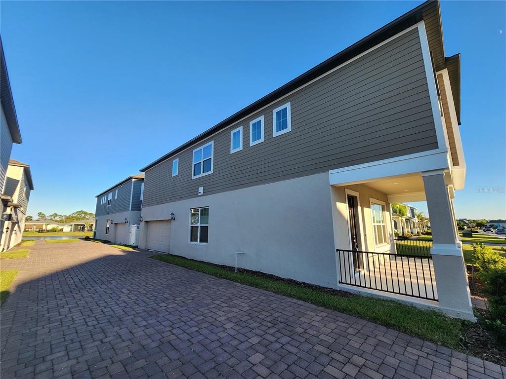 A side view of a two-story house with a paved driveway and a covered porch — 2937 MELETO BOULEVARD, NEW SMYRNA BEACH, FL