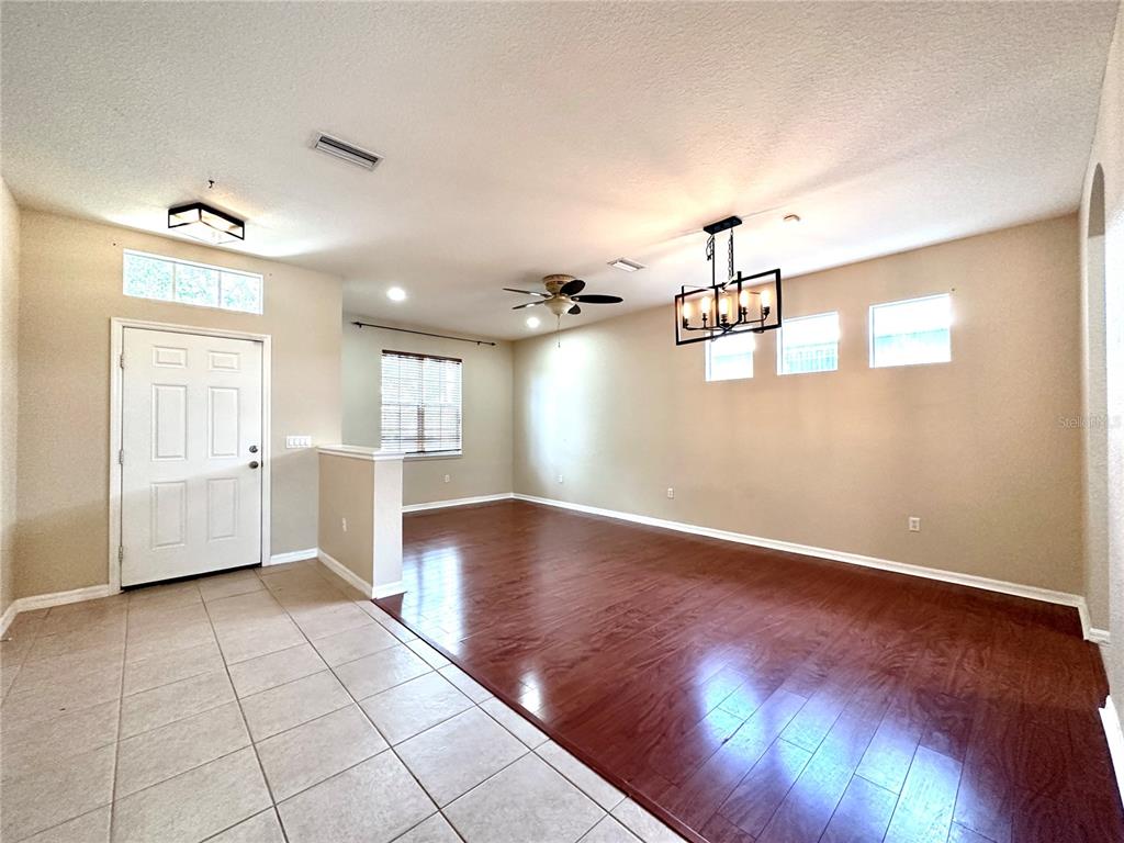 An open-concept room features a tiled entryway, hardwood flooring, a ceiling fan, and a chandelier — 1799 SCARLETT AVENUE, NORTH PORT, FL