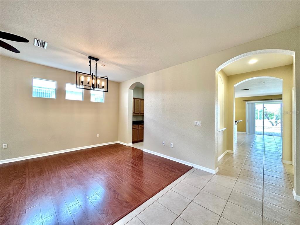 A dining room with wood flooring, a rectangular chandelier, and an arched entryway to a hallway — 1799 SCARLETT AVENUE, NORTH PORT, FL