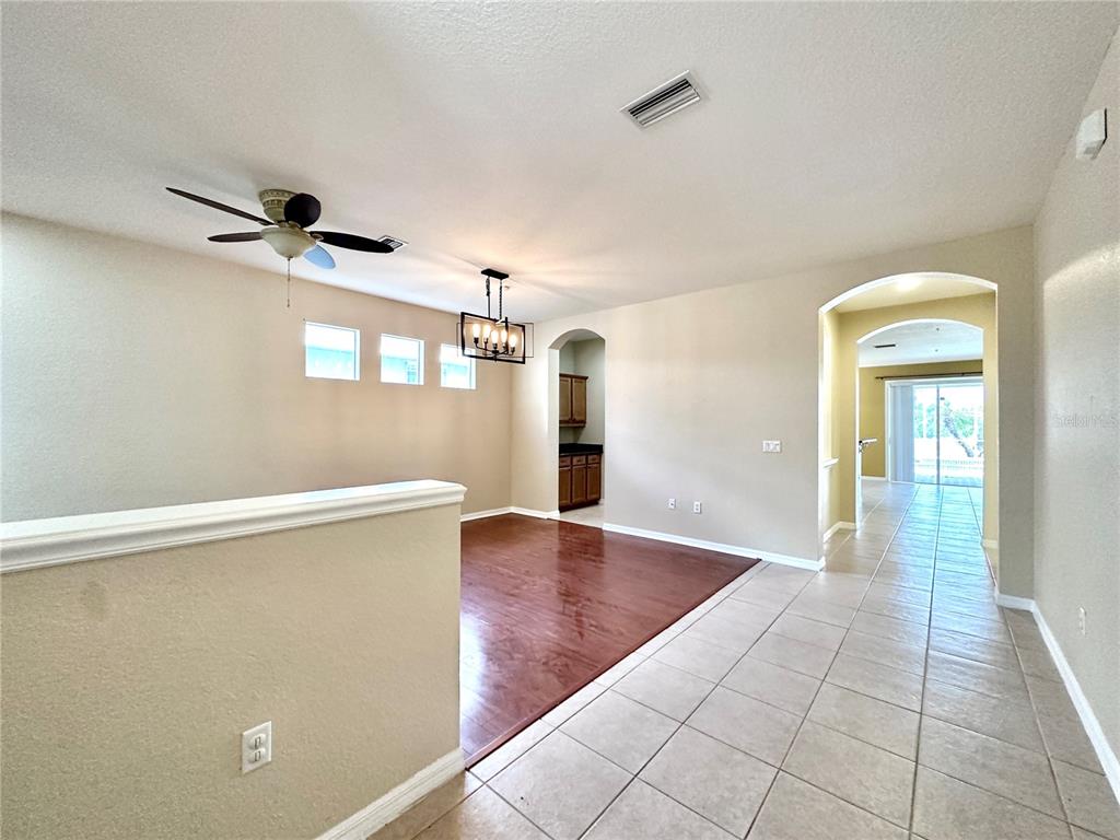A dining area with wood flooring and a chandelier sits adjacent to a tiled hallway — 1799 SCARLETT AVENUE, NORTH PORT, FL
