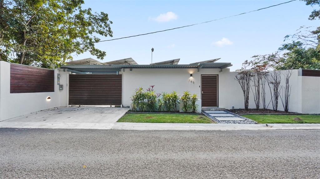 A modern house exterior features a white wall, a wooden gate, and solar panels — km 16.5 PR-15, CAYEY, PR